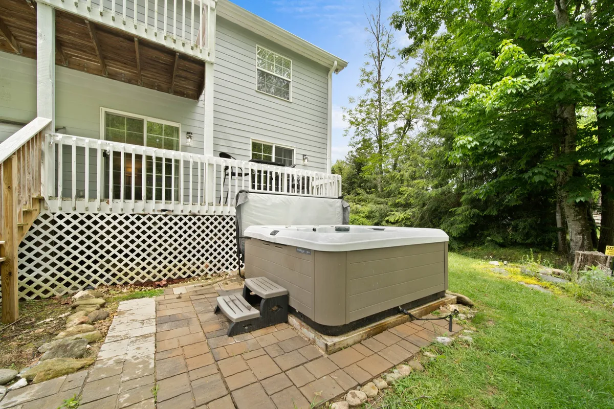 A private hot tub nestled on a deck surrounded by lush greenery, offering a tranquil space to unwind after a day of adventure. The wooden deck and verdant foliage create an inviting, serene retreat.