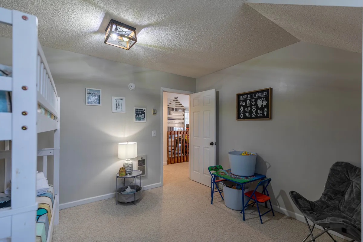 A playful and cozy kid-focused bedroom with bunk beds, a bedside table lamp, and wall art. The space is designed for both sleep and play, offering a sense of comfort and adventure for younger guests.