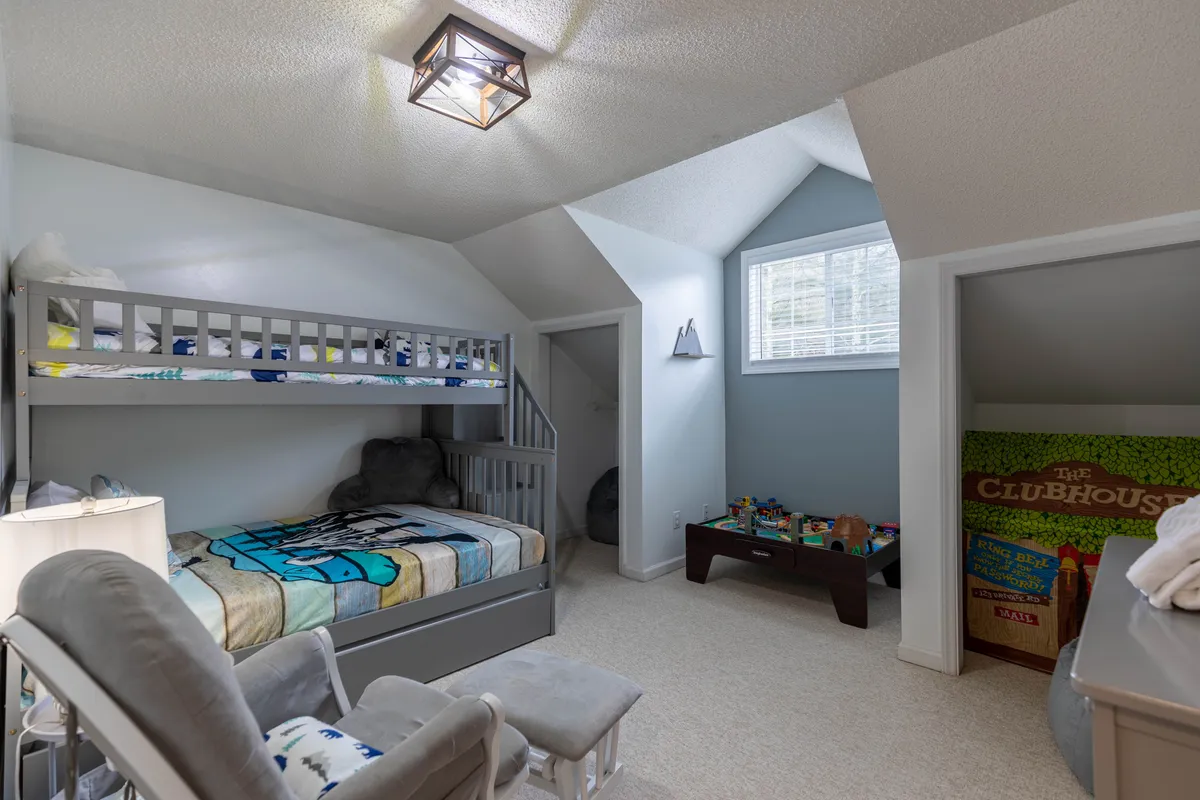 A cheerful bedroom scene featuring bunk beds, a rocking chair, a toy storage area, and a large window letting in natural light. The setup is playful and cozy, ideal for children’s playdates or sleepovers.